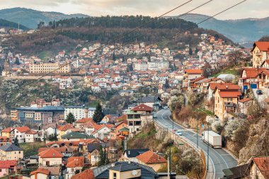 Saraybosna 'nın şehir manzarası gün batımında, renkli mahallelerde heybetli dağların zeminine dolambaçlı yollar örüyor..