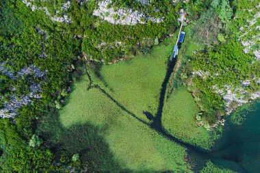 Karadağ 'ın Skadar Gölü' nün havadan manzarasında vadide yuva yapmış bir balıkçı köyü, görkemli manzaralar ve canlı ördek yosunlarıyla çevrili..