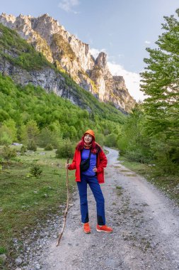 A woman hiking in the mountains, using an alpenstock to explore nature and reach the peak, experiencing the freedom and adventure of outdoor leisure. clipart