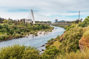 Karadağ, Podgorica, 4 Mayıs 2024: Moraca Nehri başkentten eserek, mavi suları ve çevresindeki yeşilliklerle çarpıcı bir manzara yaratarak, kenti ziyaret edilmesi gereken bir yer haline getiriyor.