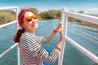 Gülümseyen dişi turist, Skadar Gölü 'nün doğal güzelliğine hayran kalarak sakin bir gezintiye çıkıyor..