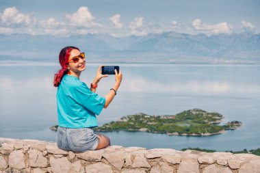 Karadağ 'ın Skadar Gölü' ne bakan mutlu Asyalı kadın, sosyal ağlar için fotoğraf çekiyor