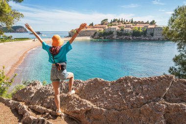 Adriyatik Denizi ve engebeli kıyı şeridi manzarasıyla Karadağlı Sveti Stefan 'ın özgürlüğünün tadını çıkaran bir gezgin.