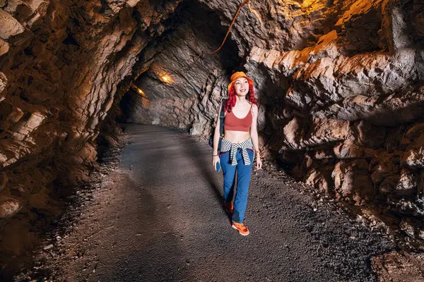 Bir dağ manzarasında manzaralı bir tünelde yürüyüş yapan maceraperest kadın yaz turizminin özünü yakalıyor.