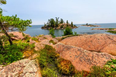 Huron Gölü kıyısında. Chikanishing Deresi 'nin ağzındaki granit kırmızısı kayalar. Georgian Körfezi. Killarney İl Parkı, Ontario, Kanada