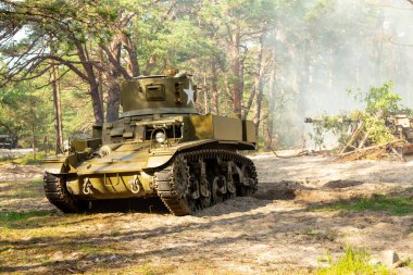 Bir Amerikan 2. Dünya Savaşı Stuart hafif tankı. Savaş alanında tanklar duman ve toz içinde.