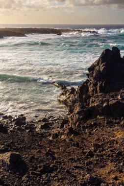 Güneş batarken Atlantik kıyısındaki siyah volkanik kayalar. Playa de las Malvas, Lanzarote, Kanarya Adaları, İspanya