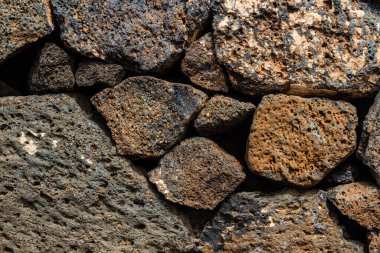 Close-up. Background. Wall of large and small natural volcanic stones. clipart