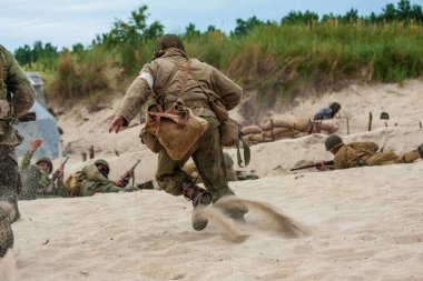 WWII  Historical reconstruction. An American medic during a battle on the beach. View from the back. clipart