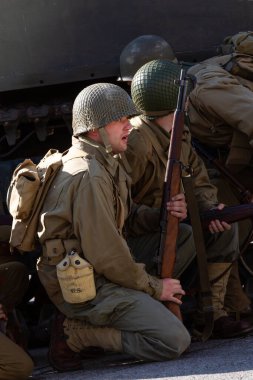 Tarihi yeniden yapılandırma. 2. Dünya Savaşı 'ndan bir Amerikan piyade askeri bir tankın arkasına saklanarak saldırmaya hazırlanıyor.. 