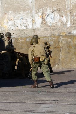 Tarihi yeniden yapılandırma. 2. Dünya Savaşı 'nın Amerikan piyade askerleri bir tankın arkasında saklanarak savaşıyor..