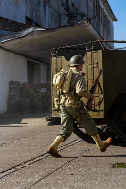 Bir 2. Dünya Savaşı piyade tümeni askeri şehir çatışması sırasında araçlar arasında koşar.