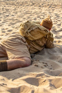 Historical reenactment. British soldier during the Second World War.  Infantry soldier prepering for shooting. View from the back clipart