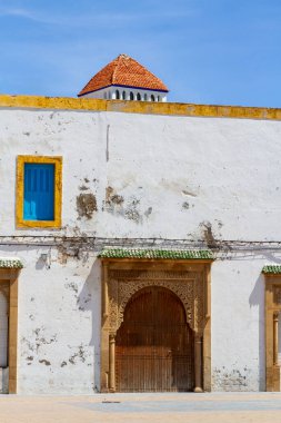 Şehir mimarisi. Geçmişi. Güzel ahşap kapısı ve mavi penceresi olan tarihi bir binanın ön cephesinin bir parçası. Essaouira, Fas, Afrika