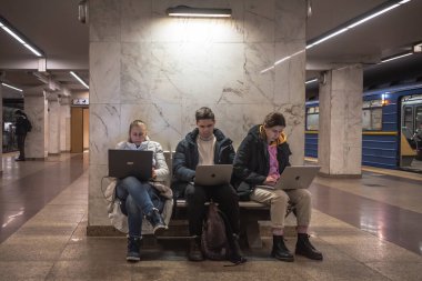 KYIV, UKRAINE - 16 Aralık 2022: Gençler, Blackou 'da internet, haberleşme, elektrik, içme suyu ve sağlık tesislerinin bulunduğu Kyiv' deki bir metro istasyonunda bilgisayarlar üzerinde çalışıyorlar