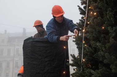 KYIV, UKRAINE - 17 Aralık 2022: Kamu hizmetleri çalışanları sisli bir günde Sofiyivska Meydanı 'nda bir Noel ağacı kurup süslediler