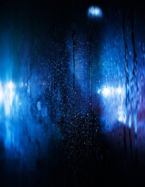 Kyiv 'de elektrik kesintisi. Kyiv sokaklarında yağmur damlaları ve karla kaplı cam vitrinler arabaların farları ve yanından geçen insanların siluetleriyle aydınlatılıyor.