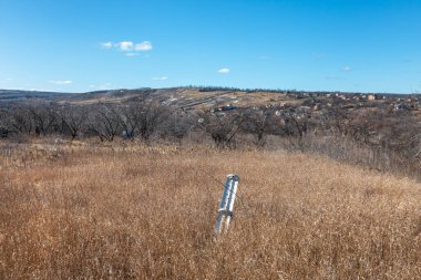 Savaş zamanı işaretleri. Bir tarlanın ortasında patlamamış bir kabuk görüldü. Harkiv 'in varoşlarında tahrip edilmiş askeri teçhizatın kalıntıları.. 
