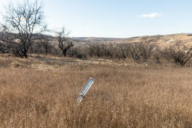 Savaş zamanı işaretleri. Bir tarlanın ortasında patlamamış bir kabuk görüldü. Harkiv 'in varoşlarında tahrip edilmiş askeri teçhizatın kalıntıları.. 