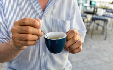 Yaşam tarzı konsepti. Sabahın erken saatlerinde açık bir kafede espresso içen yaşlı bir adam.
