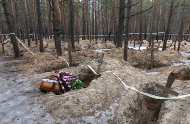 IZIUM, UKRAINE - Mar. 03, 2023: Bazı kurbanlar İzium, Harkiv bölgesi, Ukrayna 'nın dışındaki bir çam ormanında çiçek aranjmanlarıyla tabutlara gömüldü