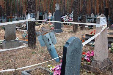 İzyum, Kharkiv reg, Ukrayna mezarlığında güvenlik bandı ile korunan patlamamış roket görülmektedir.