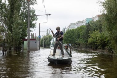 KHERSON, UKRAINE - Jun. 12, 2023: Volunteers and rescuers move by boat through flooded streets of Kherson clipart