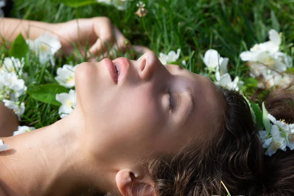 美しさ 官能性 ヌードのコンセプト 草の上に横たわる若い裸の女性のロマンチックなイメージとジャスミンの花が並ぶ — ストック写真