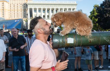 KYIV, UKRAINE - 24 Ağustos 2023: Sergiyi ziyaret edenler yanmış bir Rus tankının fıçısına yerleştirilen köpeğin fotoğraflarını çekiyorlar.