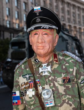 KYIV, UKRAINE - 24 Ağustos 2023: Kyiv 'in merkezinde Rus askeri teçhizatının yok edildiği bir sergi sırasında Putin maskesi ve Rus faşist sembolleri takan bir adam.