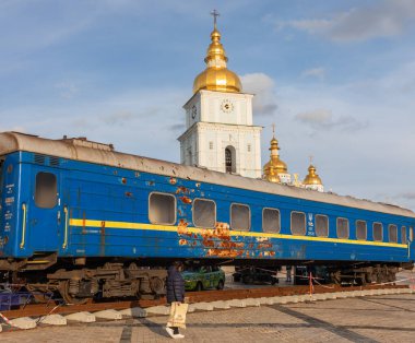 Kyiv 'deki Mykhailivska Meydanı' ndaki Mykhailivska Kilisesi önünde Rus askerleri tarafından vurulan bir Ukrayna demiryolu vagonu görülüyor.. 