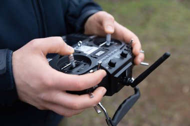 LVIV, UKRAINE - 11 Şubat 2024: Bir FPV insansız hava aracının kendi kendini yöneten uçuş eğitimi sırasında uzaktan kumandayla uçmasını kontrol eden genç bir adam görülüyor 