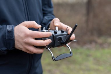 LVIV, UKRAINE - 11 Şubat 2024: Bir FPV insansız hava aracının kendi kendini yöneten uçuş eğitimi sırasında uzaktan kumandayla uçmasını kontrol eden genç bir adam görülüyor 