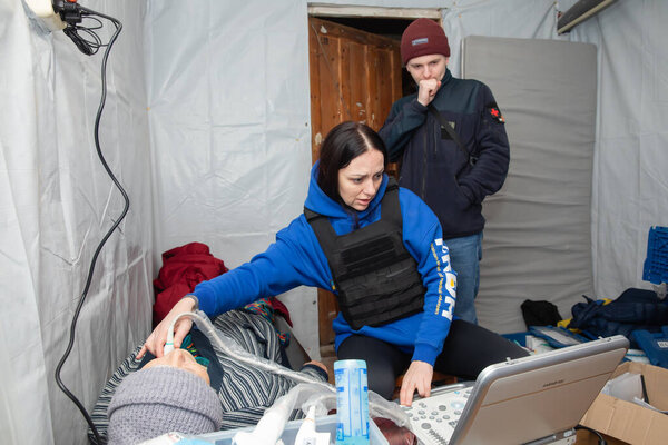 SIVERSK, DONETSK REG., UKRAINE - Mar. 10, 2024: A woman ultrasound doctor from the Frida Ukraine Volunteer Mission is seen providing an ultrasound scan to a local resident woman.