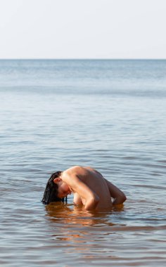 Deniz kenarında çıplak poz veren güzel bir kadın.