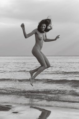 Deniz kenarında çıplak poz veren güzel bir kadın.