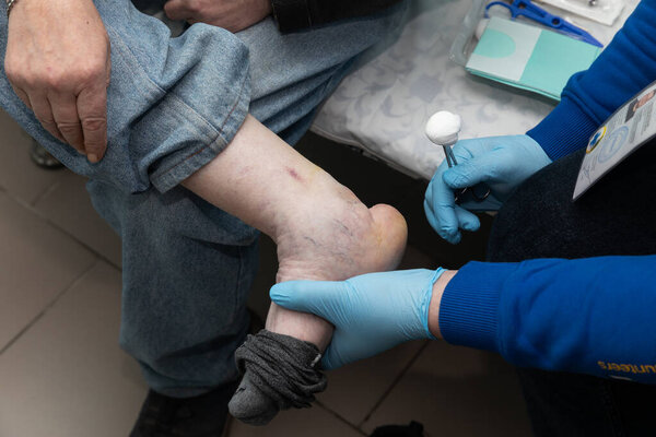 DONETSK Reg, UKRAINE - Apr. 20, 2024: A trauma doctor from Frida Volunteer Mission is seen examining the leg of an elderly man