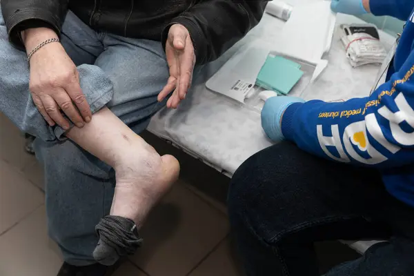 Donetsk Reg Ukraine Aapril 2024年2月20日 弗里达义工团的一位创伤医生正在检查一位老人的腿 免版税图库图片