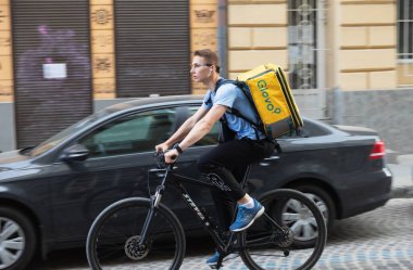 IV, UKRAINE - Mayıs. 18, 2024: Bir Glovo yemek dağıtım kuryesi, Lviv 'in eski tarihi bölgesinde müşterilere bisiklet sürerken görüldü