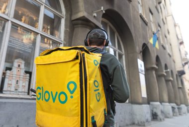 IV, UKRAINE - Mayıs. 18, 2024: Bir Glovo yemek servis kuryesi Lviv 'in eski tarihi bölümünde sokakta görüldü