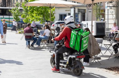 IV, UKRAINE - Mayıs. 19, 2024: Bir Bolt yiyecek dağıtım kuryesi, Lviv 'in eski tarihi merkezinin caddelerinde motosikletiyle müşterilerine koşarken görülüyor.