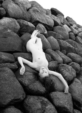 Genç bir kadın sahilde çıplak poz veriyor, eski bir taş iskelede. Ainazi Kuzey İskelesi