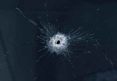 Kurşunla delinmiş bir araba camı. Kırık cam ve delik.