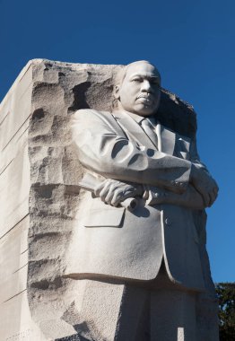 Washington DC, ABD - 10 Ekim 2022: Martin Luther King Jr., Dr. King 'in kolları çaprazlanmış büyük taş bir heykeli, bir parşömen tutuyordu. Anıt açık mavi bir gökyüzüne karşı duruyor.