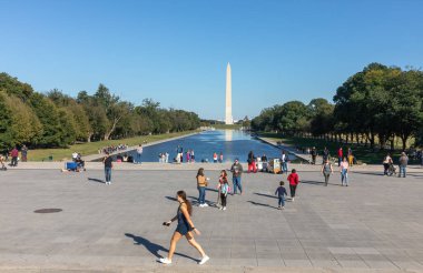 Washington DC, ABD - 10 Ekim 2022: İnsanlar güzel bir günde yakalanan Washington Anıtı ve çevre parkın manzarası önünde dinleniyor.