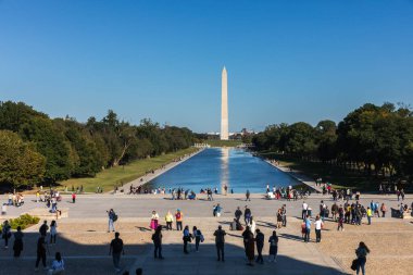 Washington DC, ABD - 10 Ekim 2022: İnsanlar güzel bir günde yakalanan Washington Anıtı ve çevre parkın manzarası önünde dinleniyor.