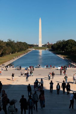 Washington DC, ABD - 10 Ekim 2022: İnsanlar güzel bir günde yakalanan Washington Anıtı ve çevre parkın manzarası önünde dinleniyor.