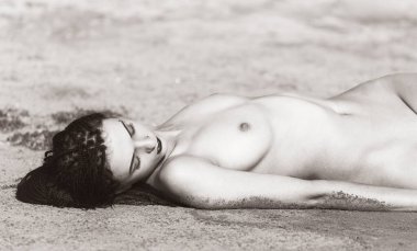 Kızıl saçlı genç kadın deniz kenarında çıplak poz veriyor. Gençlik, güzellik ve çıplaklık kavramı.