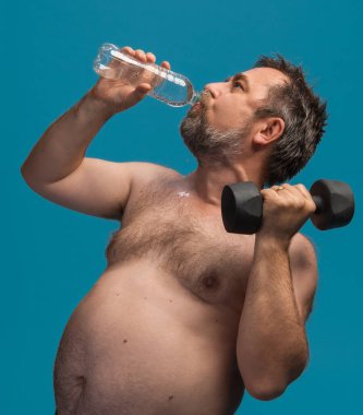 An elderly man lifts a dumbbell while drinking water to stay hydrated. He is focused on his fitness routine in a bright setting, showcasing an active lifestyle and dedication to health. clipart