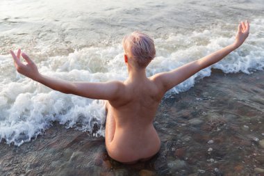 Yaşam tarzı ve güzellik konsepti. Güzel çıplak kadın doğanın tadını çıkarıyor. Deniz kıyısında seksi çıplak kadın.